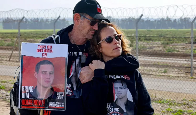 Relatives of Israeli hostages held by the Palestinian Hamas movement carry a picture of Omer Neutra, 22, in Kibbutz Nirim along the fence on the Gaza border, equipped with powerful loudspeakers hanging from cranes, in an effort to get messages of hope across to them as their time in captivity nears to 100 days, on January 11, 2024. The conflict triggered by Hamas's deadly October 7 attack on Israel has caused massive destruction in the Gaza Strip, killing tens of thousands and leaving residents on the brink of famine. Much of the territory has become unrecognisable, as entire neighbourhoods which were once bustling with people, cars and donkey-drawn carts have been reduced to rubble. (Photo by JACK GUEZ / AFP) (Photo by JACK GUEZ/AFP via Getty Images)