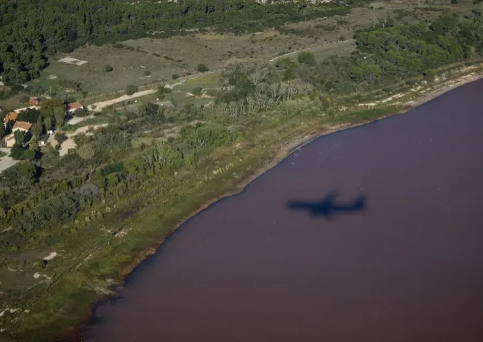This photograph shows an aerial view of a shadow of a plane flying over the pink Lavalduc Lake in Istres, southeastern France, on October 4, 2024. (Photo by CLEMENT MAHOUDEAU / AFP) (Photo by CLEMENT MAHOUDEAU/AFP via Getty Images)