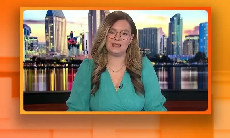 Video still of the host of Tipping Point at the desk of their talk show on One America News Network.